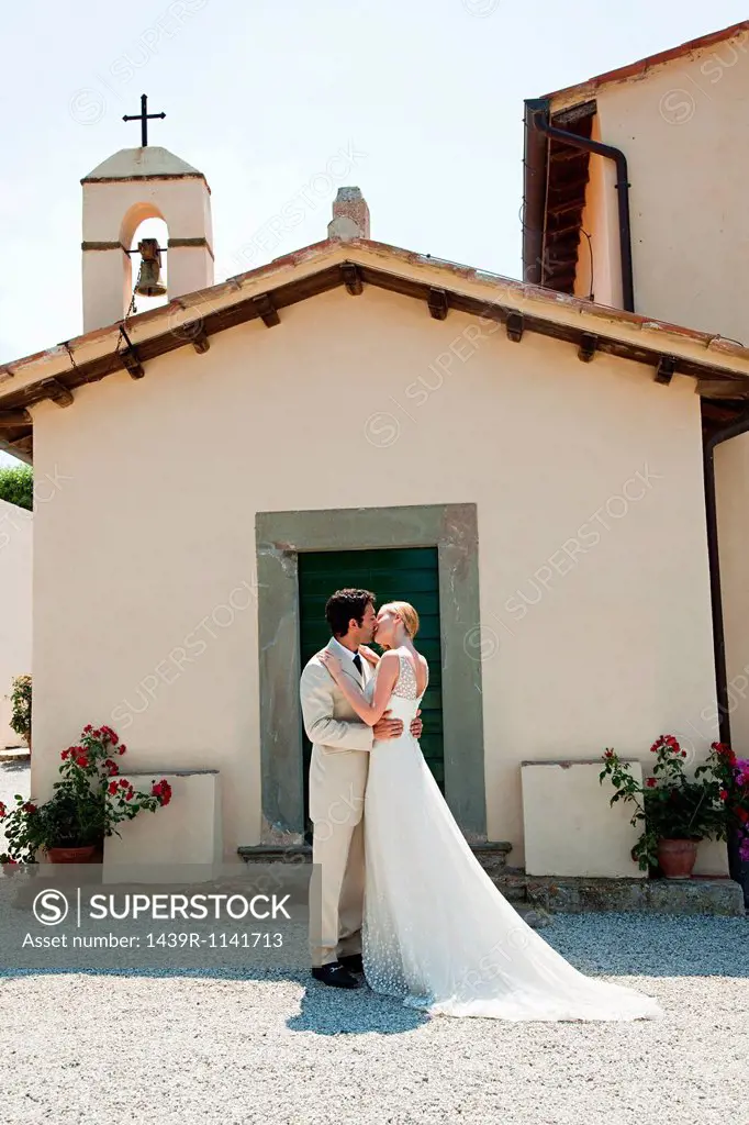 Newlyweds outside church, kissing