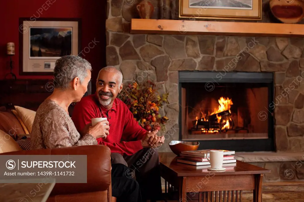 Mature couple sitting by fireplace