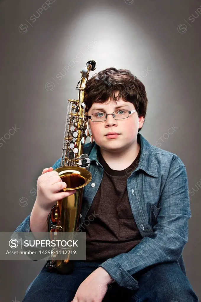 Portrait of young teenage boy holding saxophone