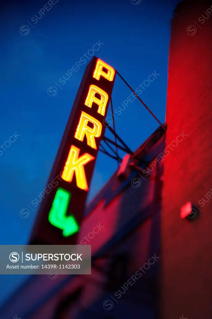 Illuminated neon parking sign on building