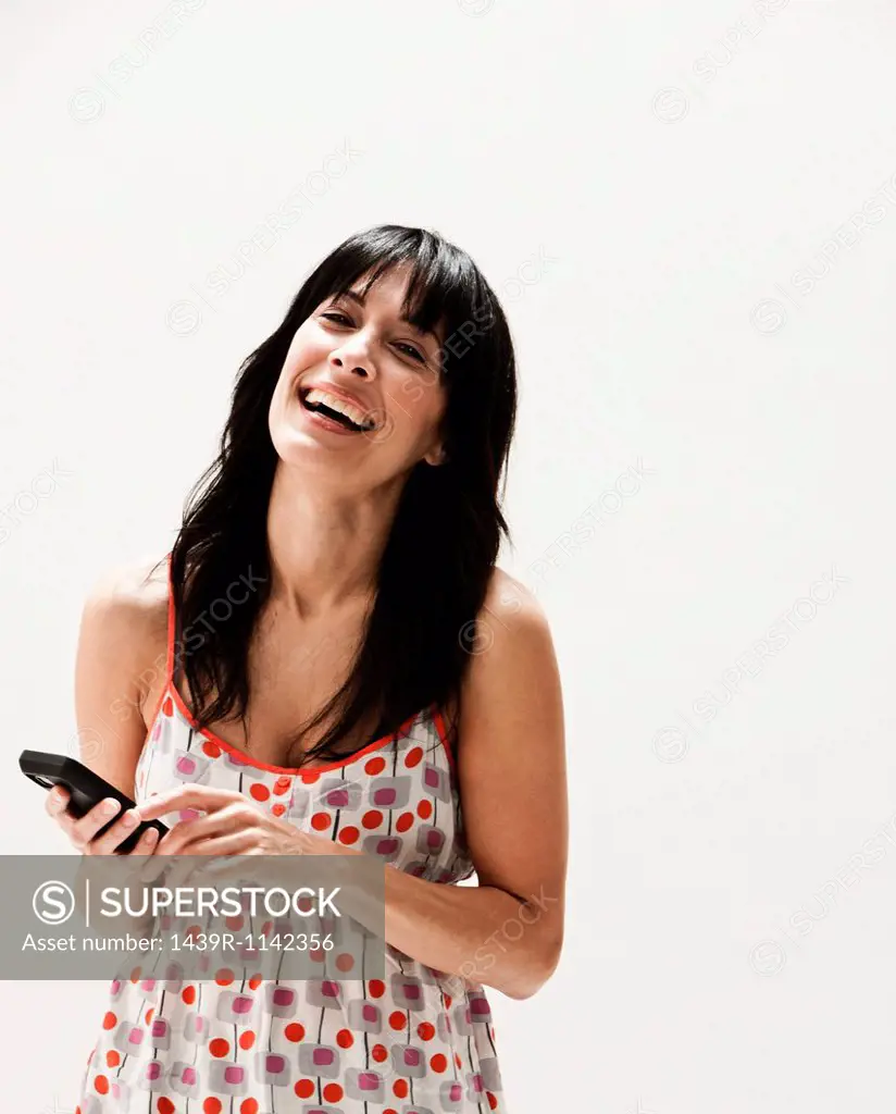 Smiling mature woman using cellphone, studio shot