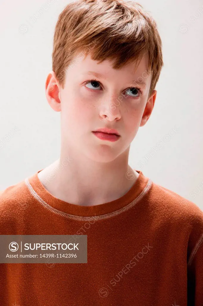 Boy in brown sweater rolling eyes, studio shot