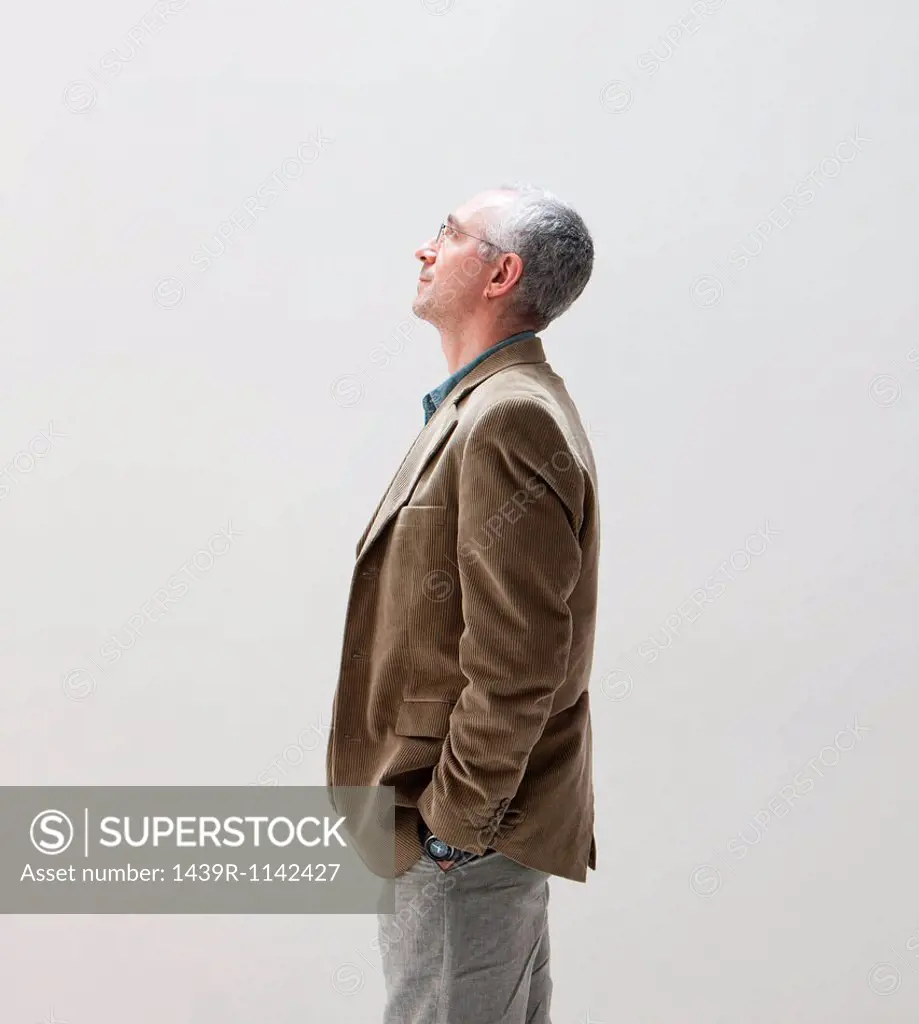 Mature man with hands in pocket looking up, studio shot