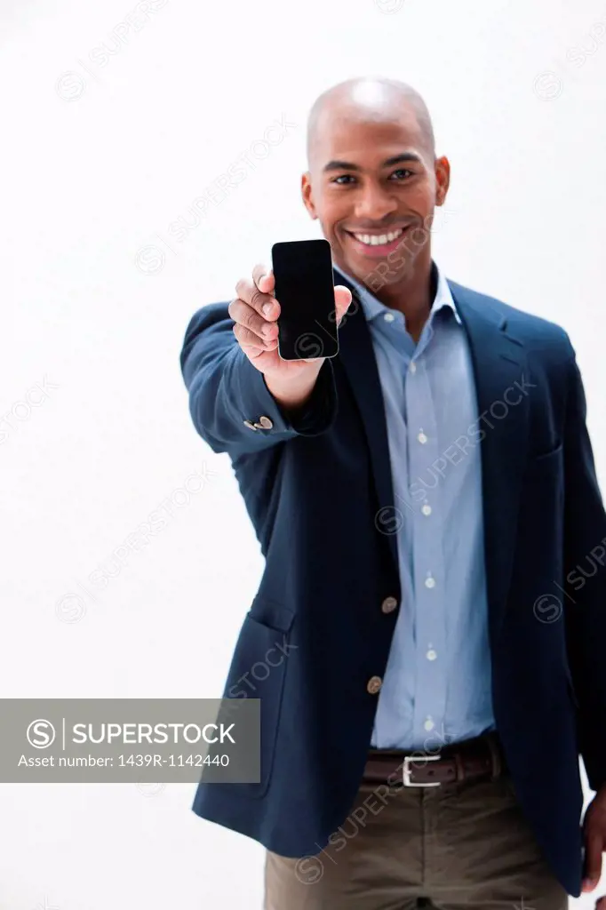 Portrait of African American man holding cellphone, studio shot