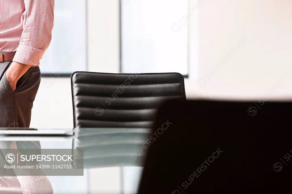 Businessman by desk with hand in pocket