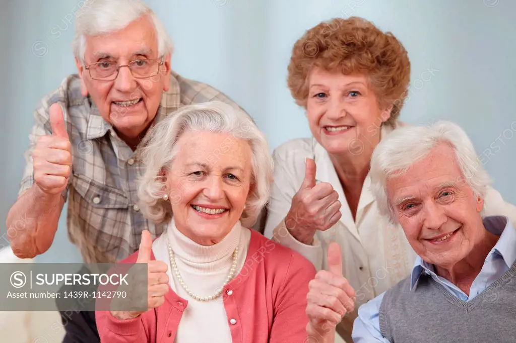 Four seniors with thumbs up, portrait