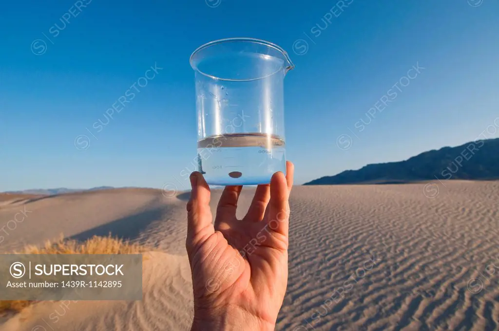 Man holding water in beaker in Death Valley National Park, California, USA