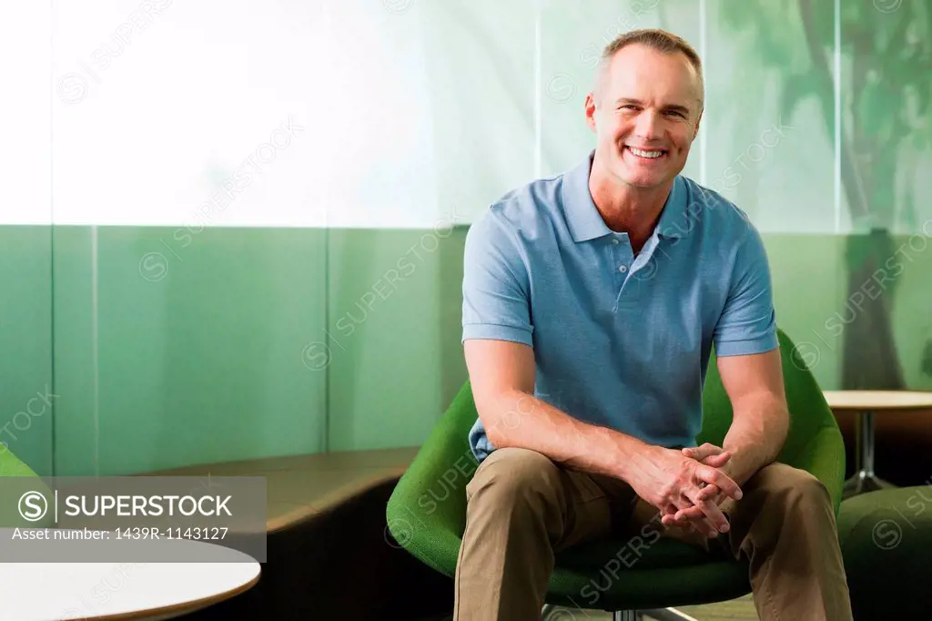 Portrait of mature man sitting in green chair in office