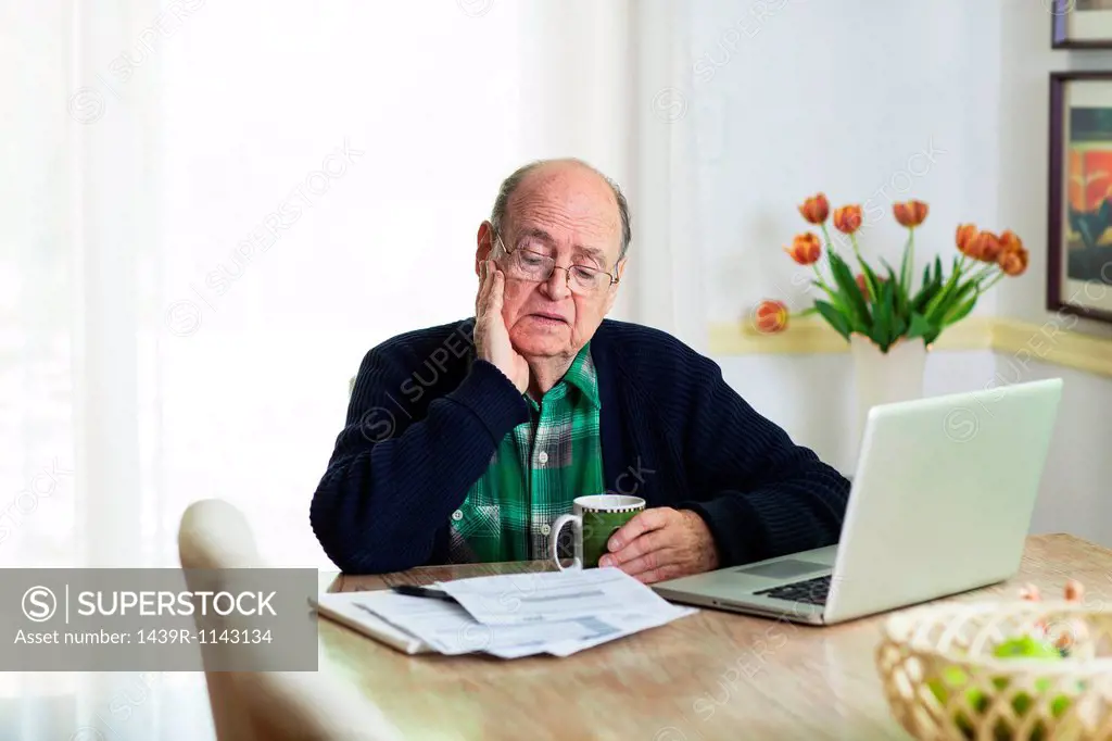 Senior man looking at documents on desk at home