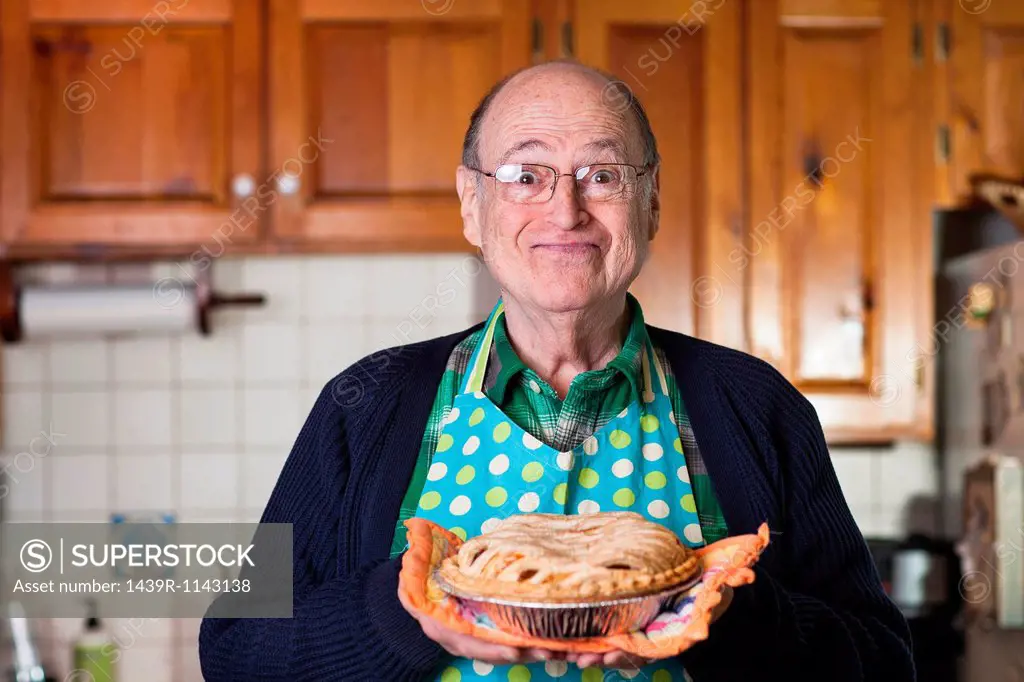Senior man holding freshly baked pie, portrait