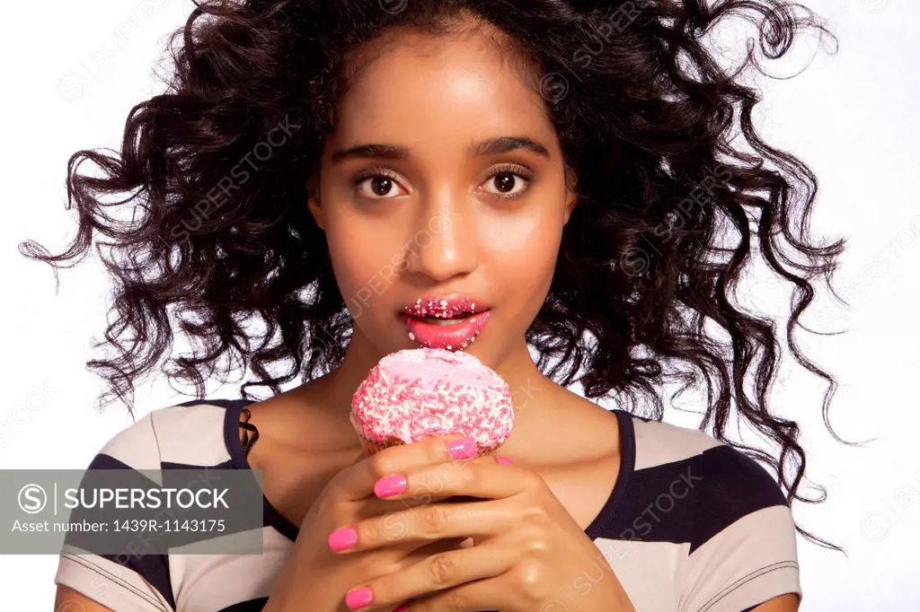 Young woman eating cupcake, studio shot