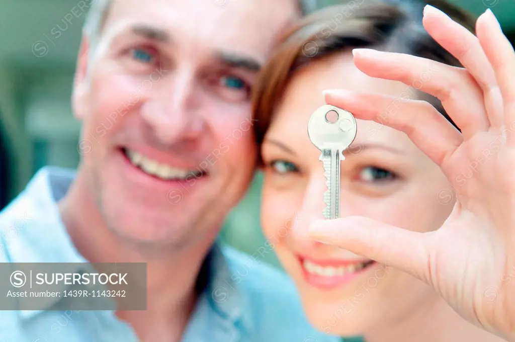 Woman holding house key, man in background