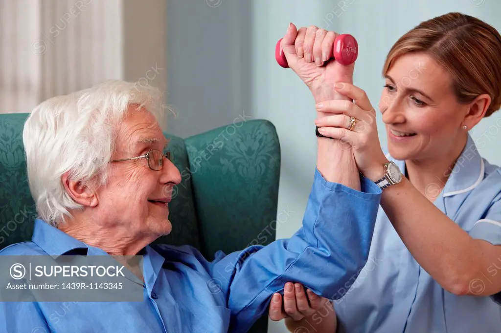 Carer assisting senior man with hand weights