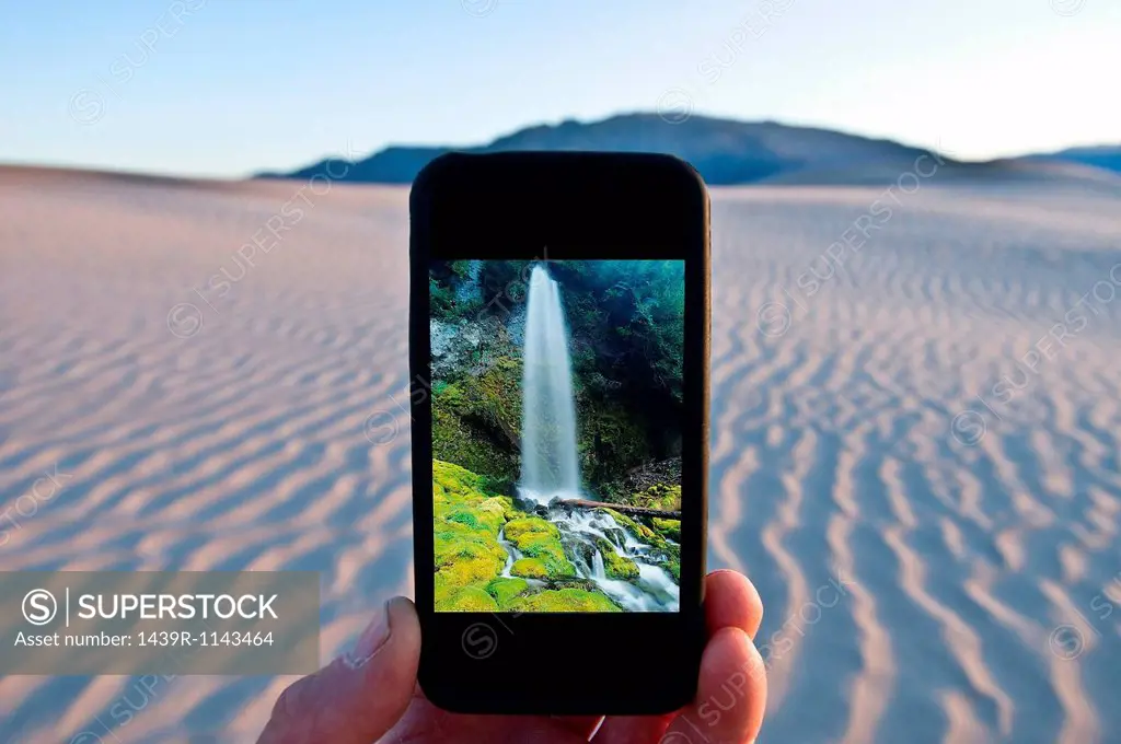 Man holding cellphone with waterfall image in Death Valley National Park, California, USA
