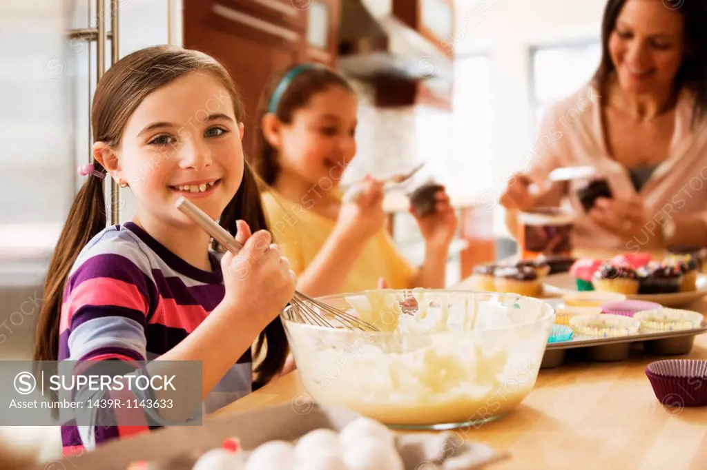 Portrait of girl making cakes with family in kitchen