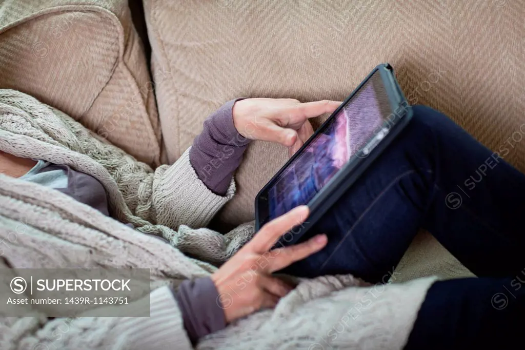 Senior woman using digital laptop on sofa, mid section