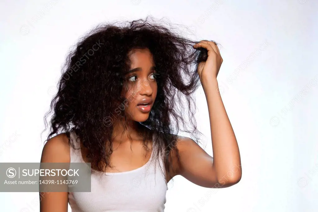 Young woman holding hair against white background