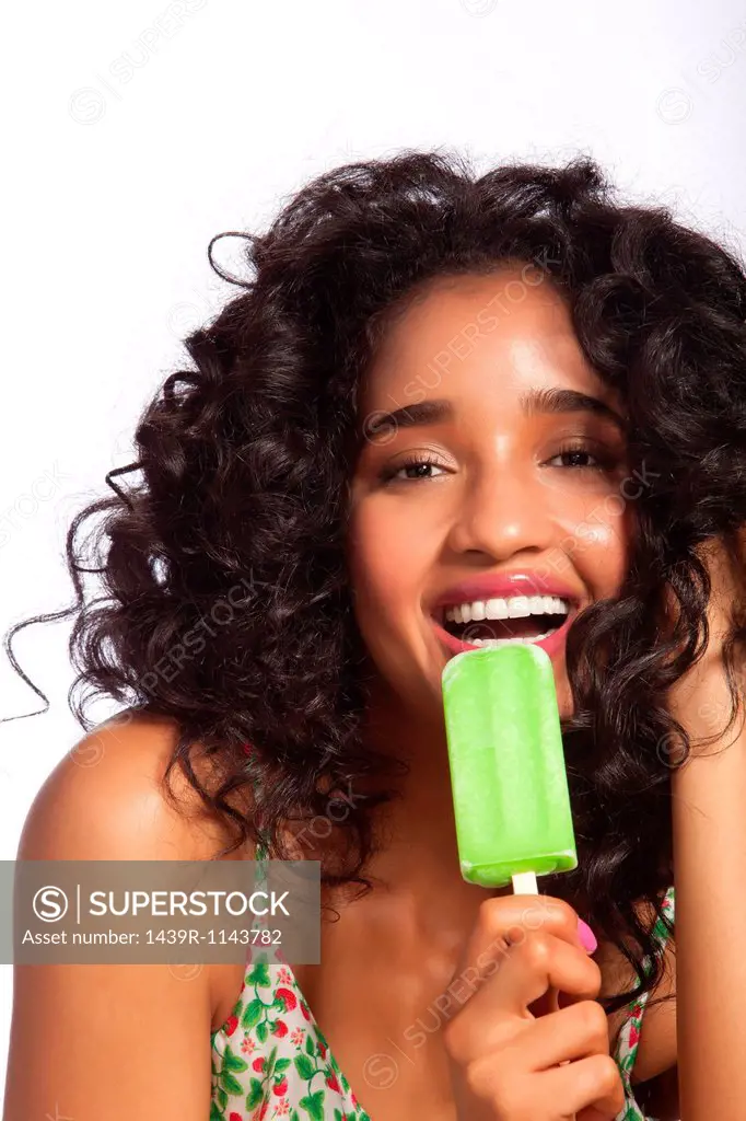 Young woman eating green popsicle, portrait