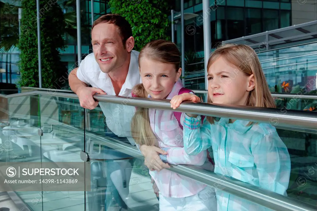 Father with two daughters leaning on railing