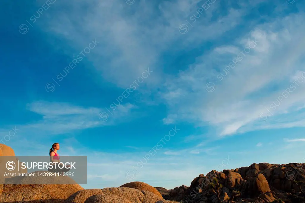 Woman meditating on desert rocks
