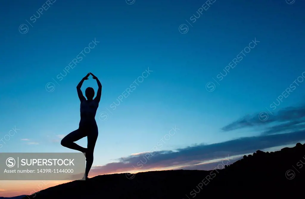 Young woman in tree pose in desert, silhouette