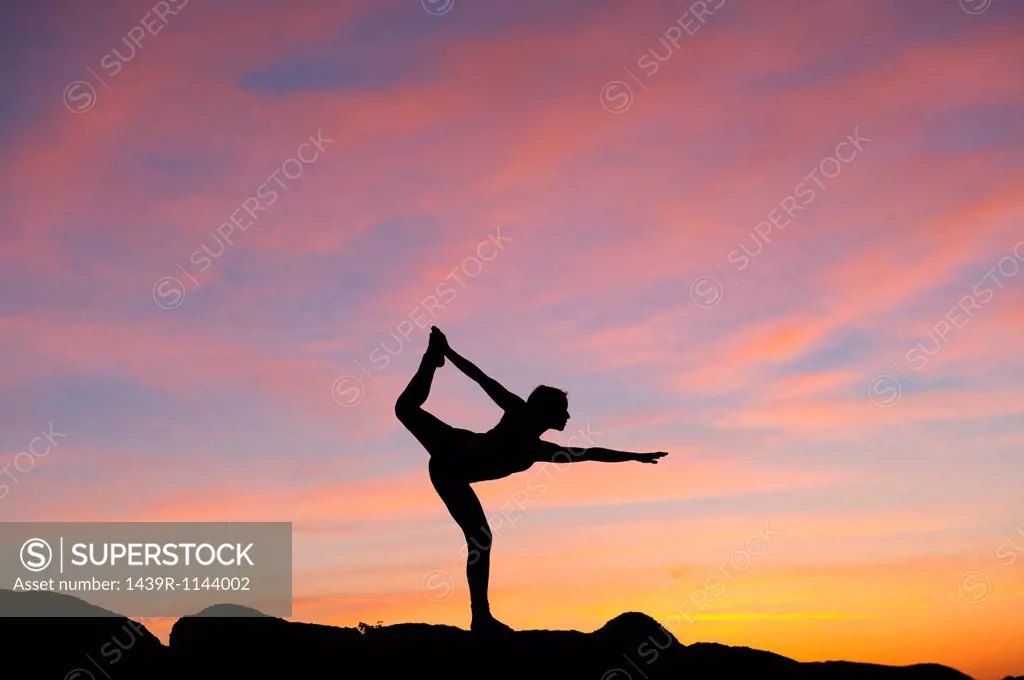 Young woman in dancer pose in desert, silhouette