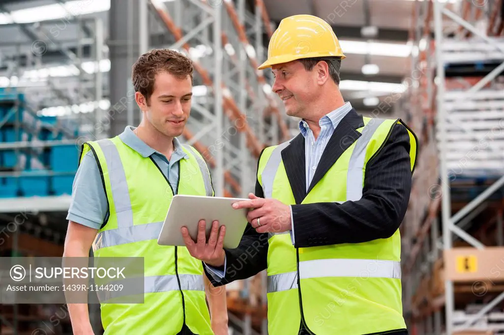 Men in warehouse using digital tablet