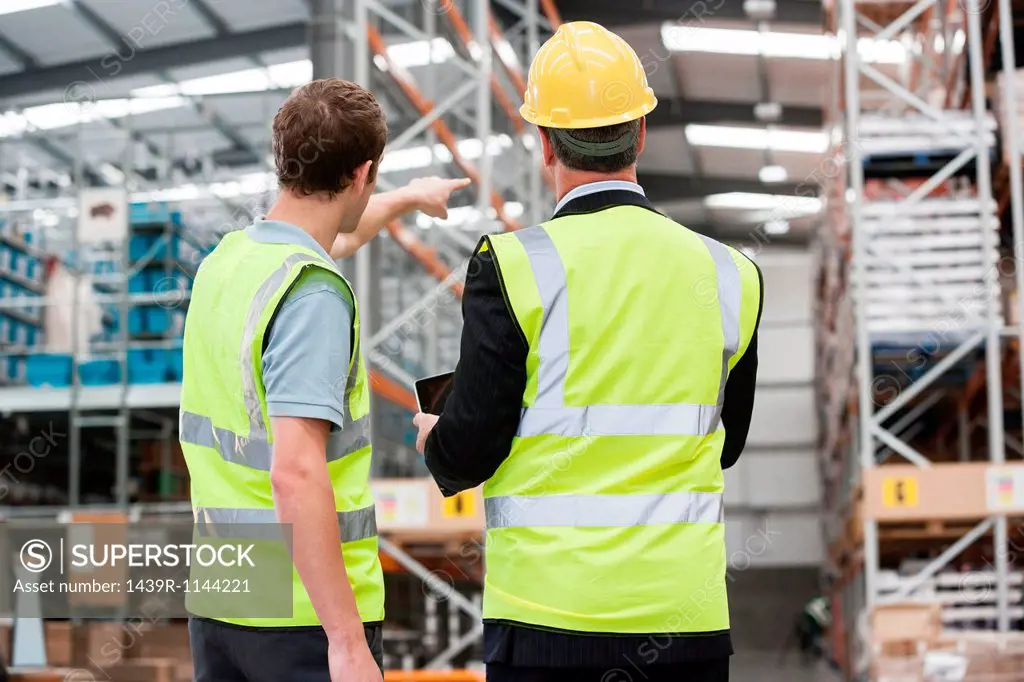 Two men in warehouse, one pointing