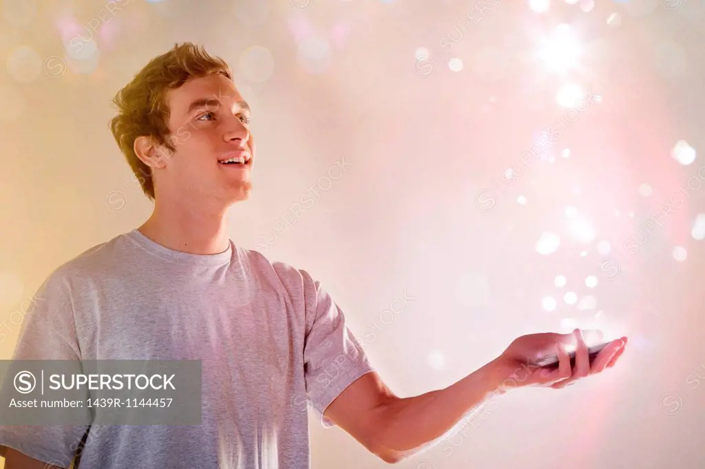 Young man looking at lights coming from cellphone