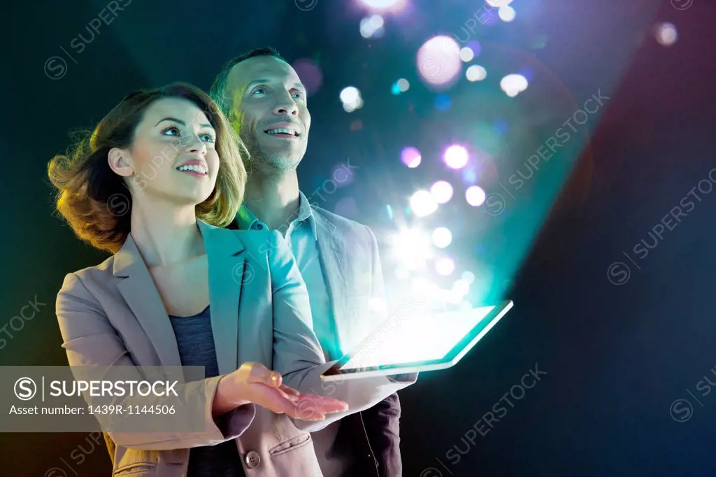 Businesspeople looking at lights coming from digital tablet