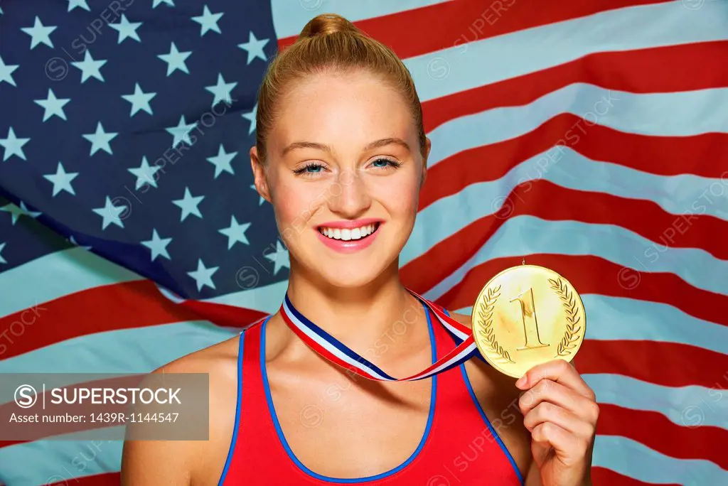 Young woman in front of USA flag with gold medal