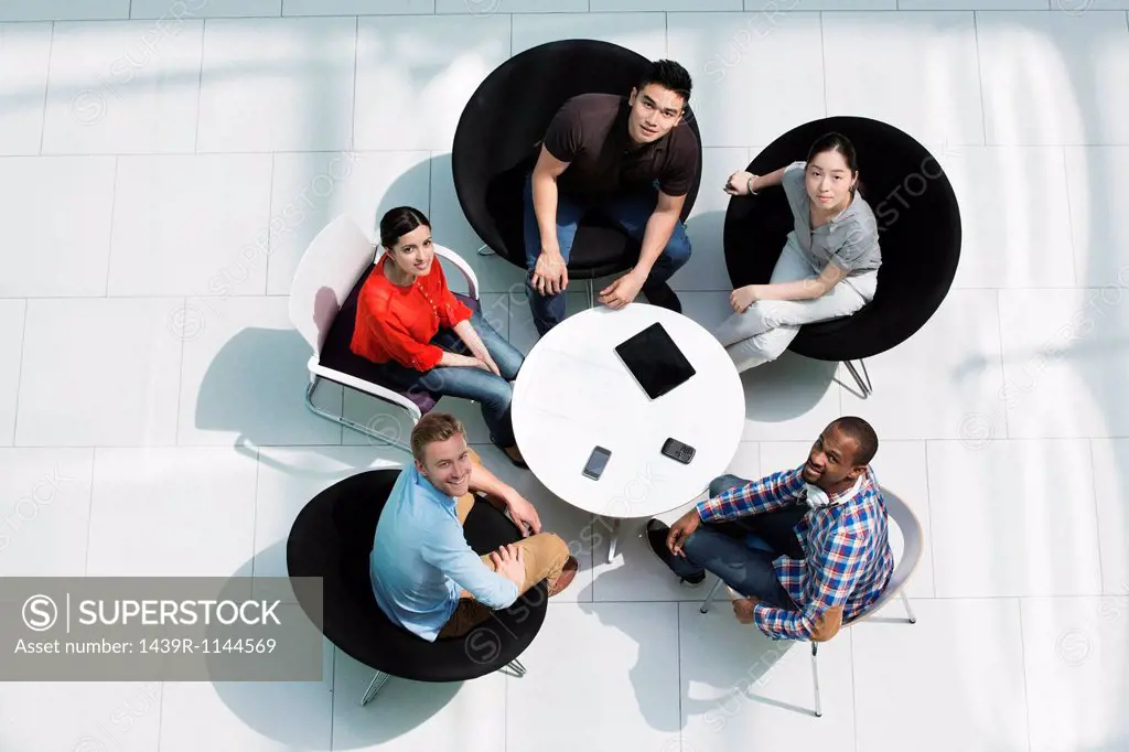 Overhead view of colleagues in meeting, looking up at camera