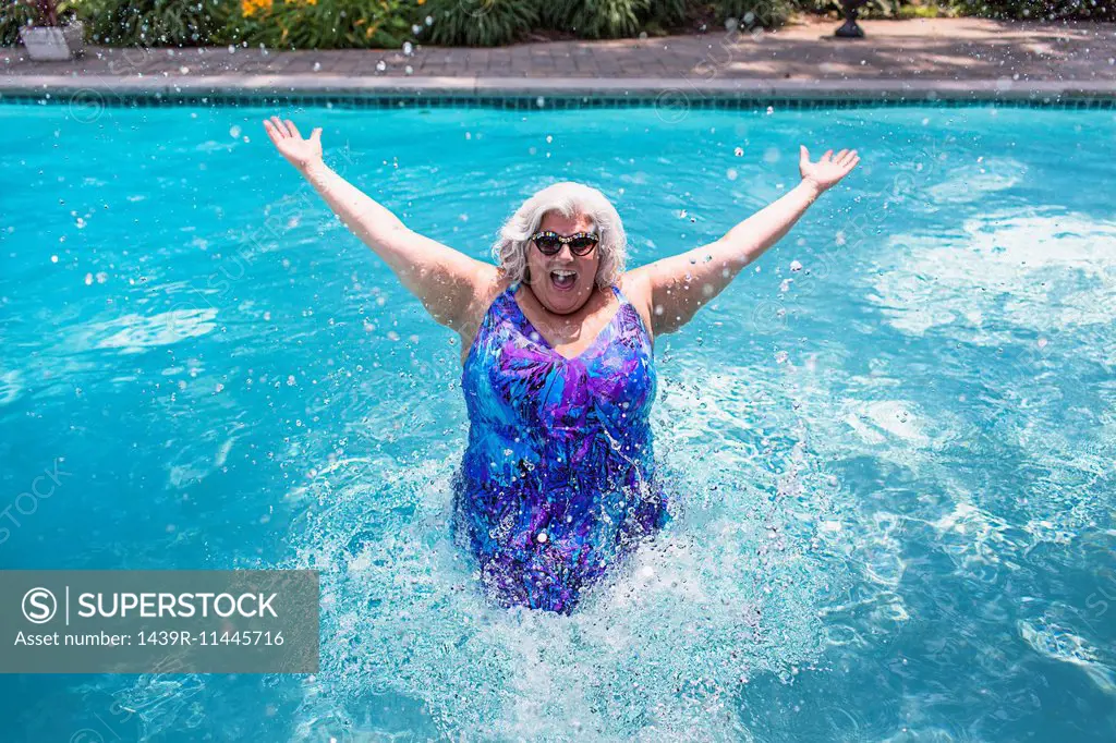 Portrait of mature woman splashing about in swimming pool