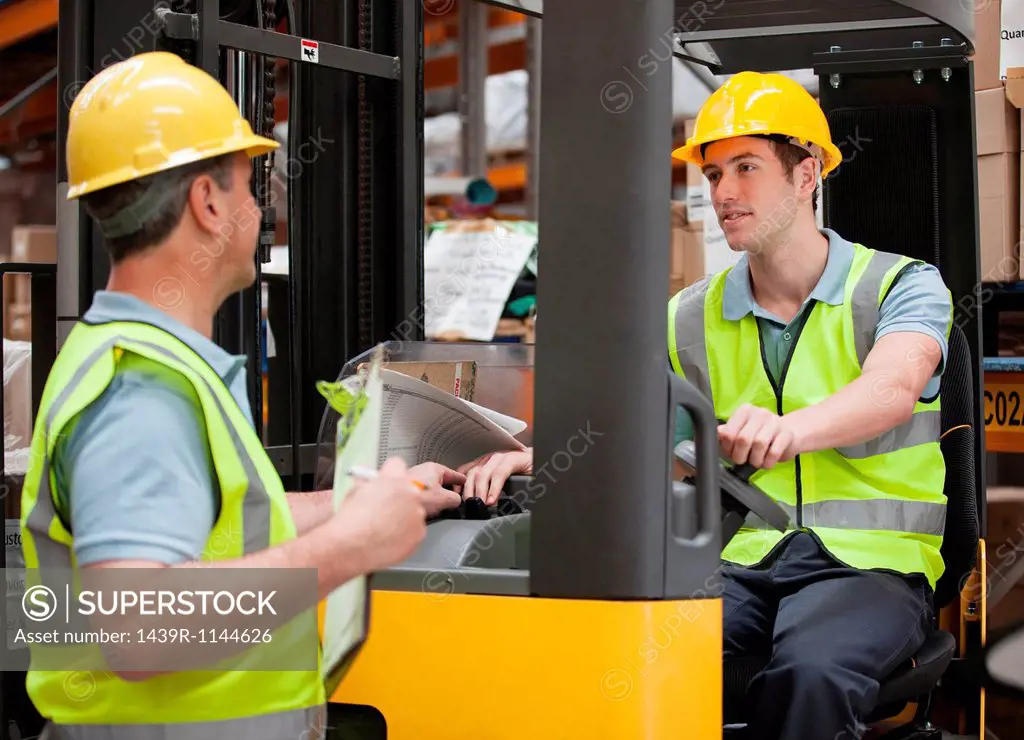 Two men in warehouse, one on forklift truck