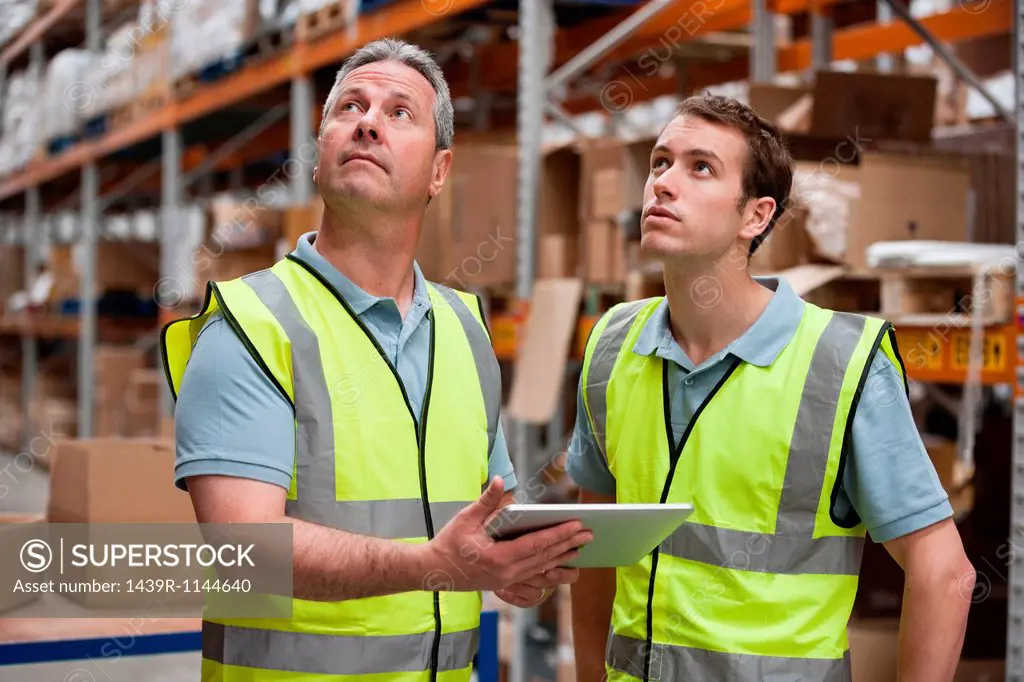 Men in warehouse using digital tablet