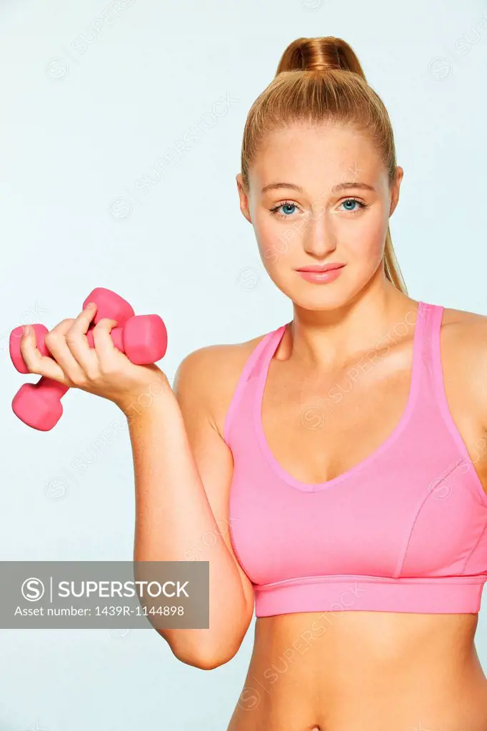 Young woman using hand weights, looking unimpressed