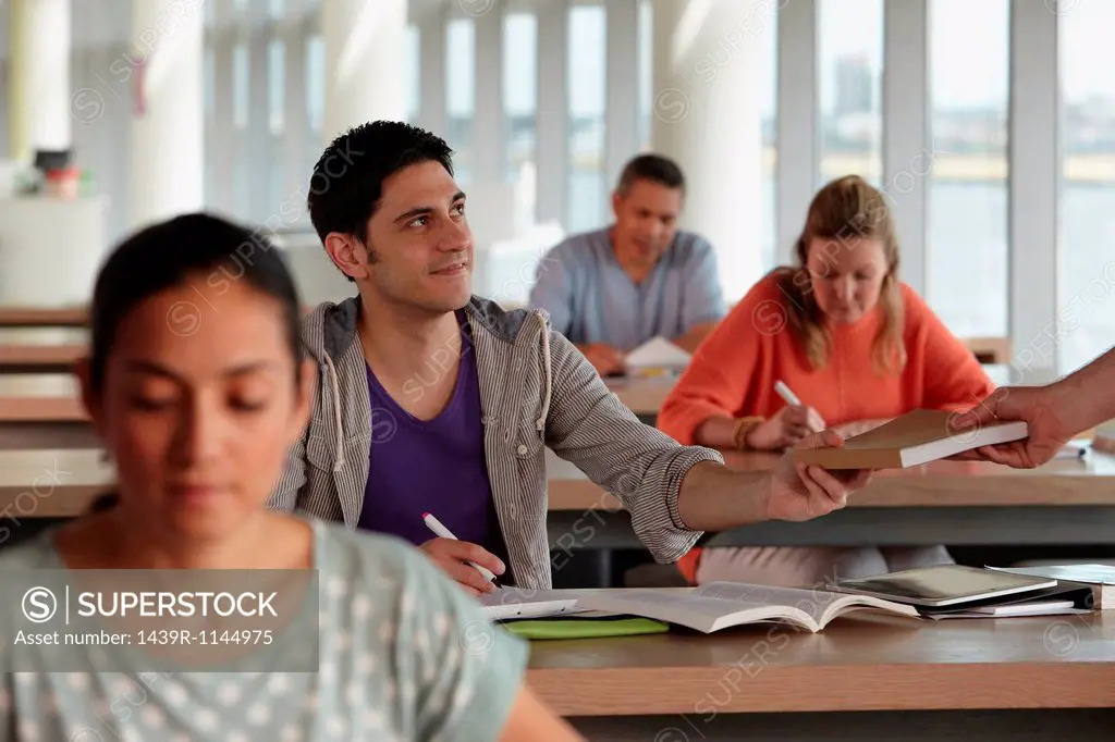 Mature students in class, man receiving book