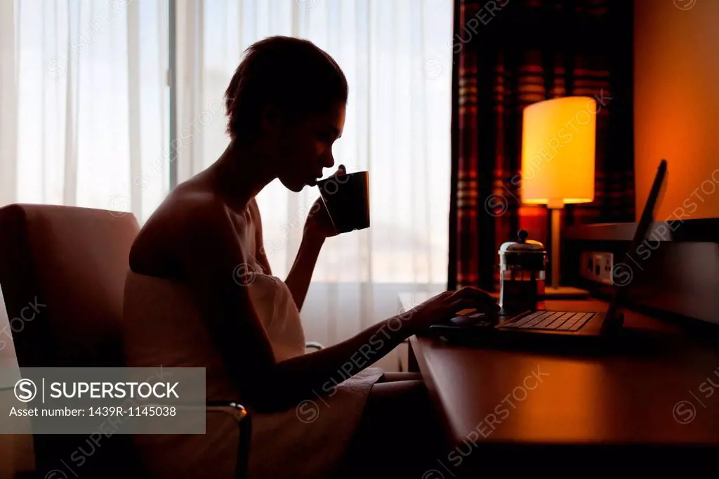 Young woman sitting at laptop in hotel room