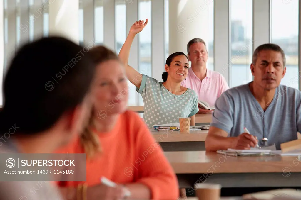 Mature students in class, woman with hand up