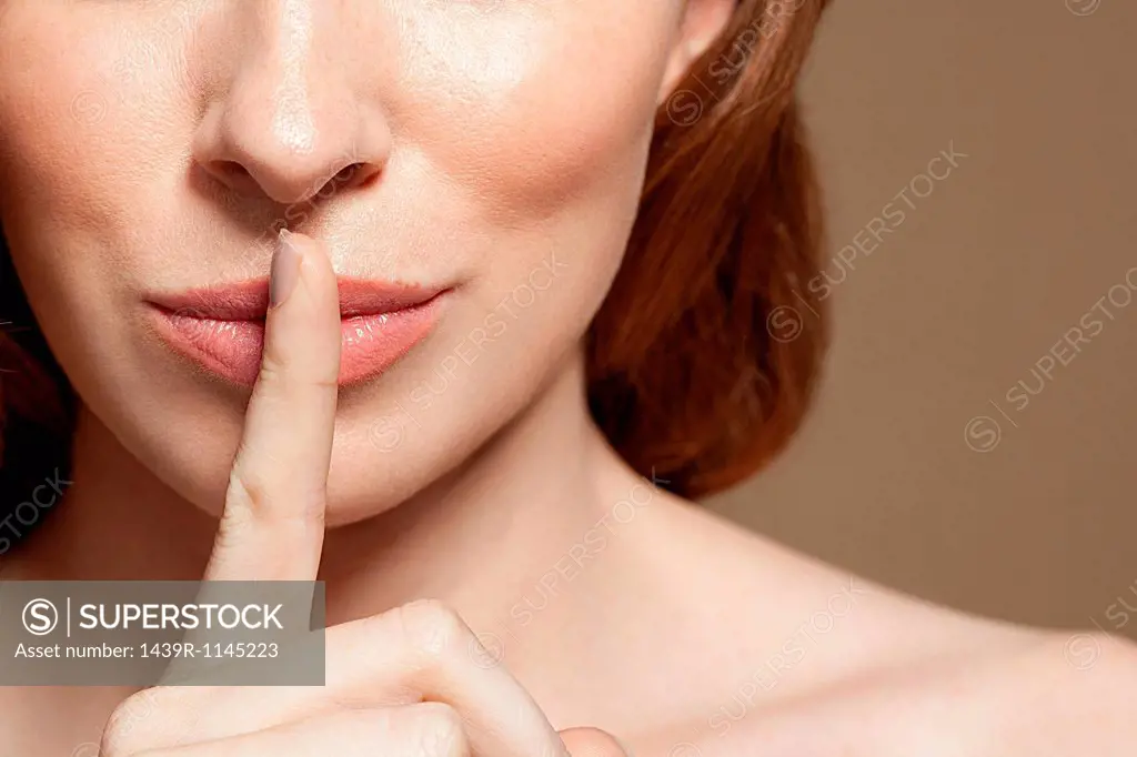 Woman with finger on lips, close up