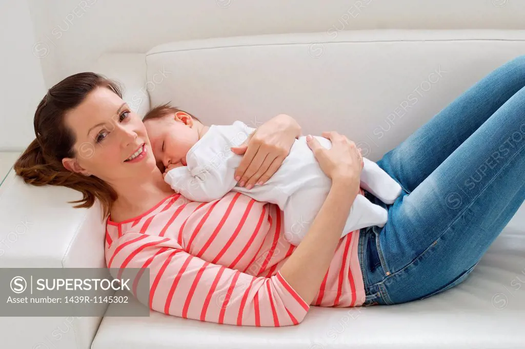 Woman and baby girl resting on sofa