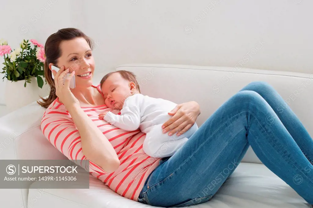 Mother on sofa with baby whilst on cellphone