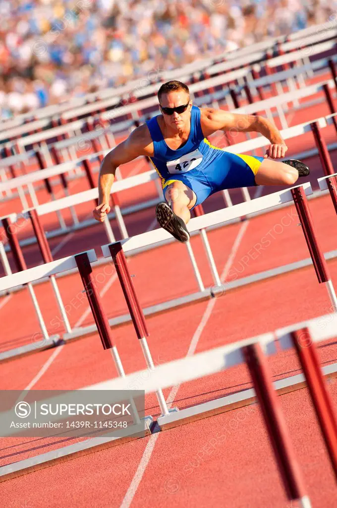 Male hurdler clearing hurdles