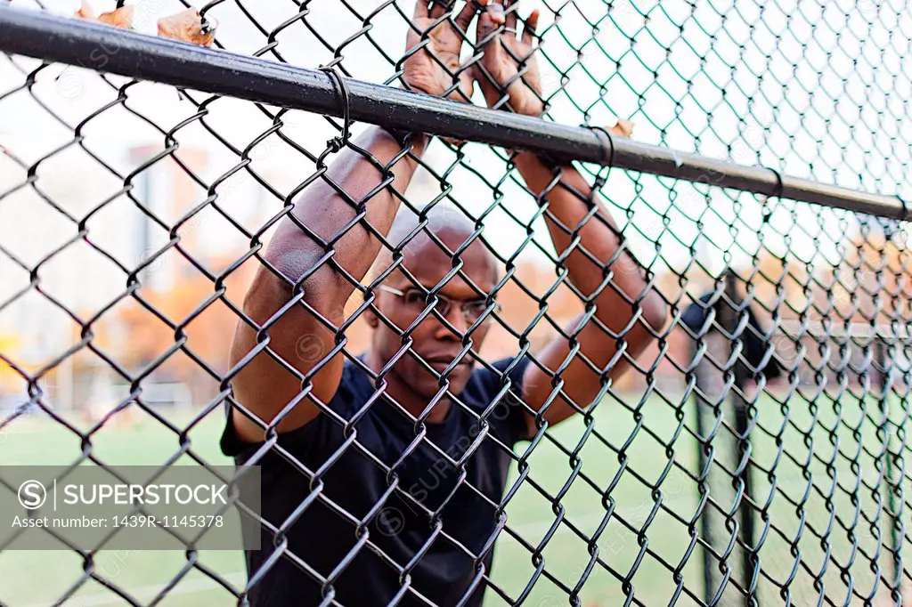 Man leaning on chain link fence