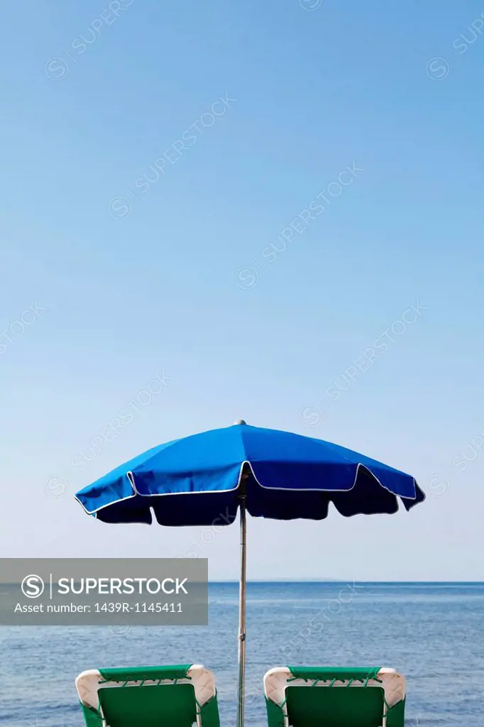 Blue parasol and sun loungers by the sea