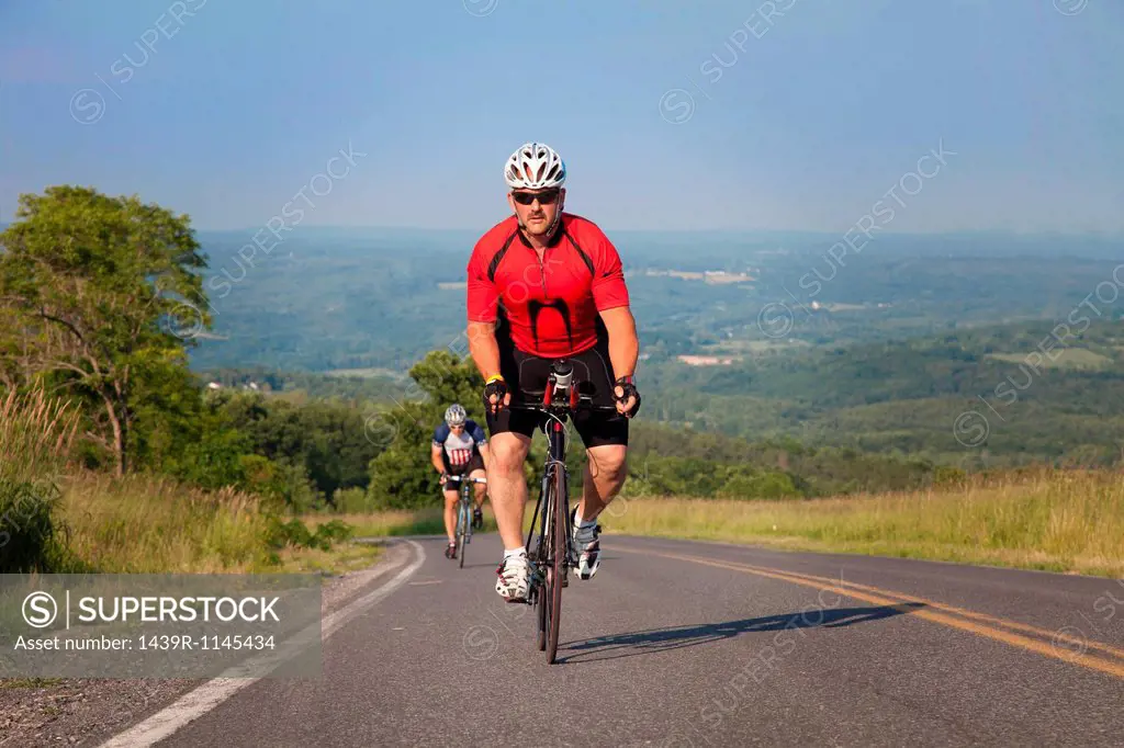 Men cycling on open road