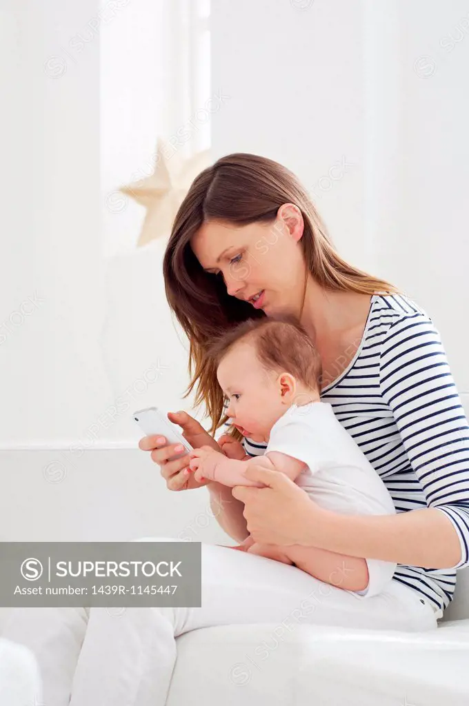 Mother holding baby and using cellphone