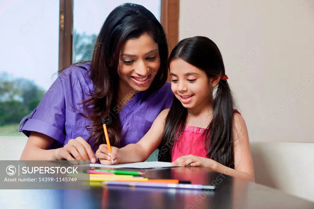 Girl writing while her mother looks on