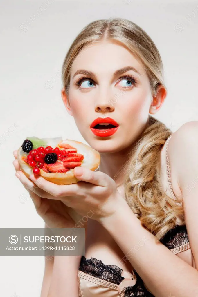 Young woman holding fresh fruit tart