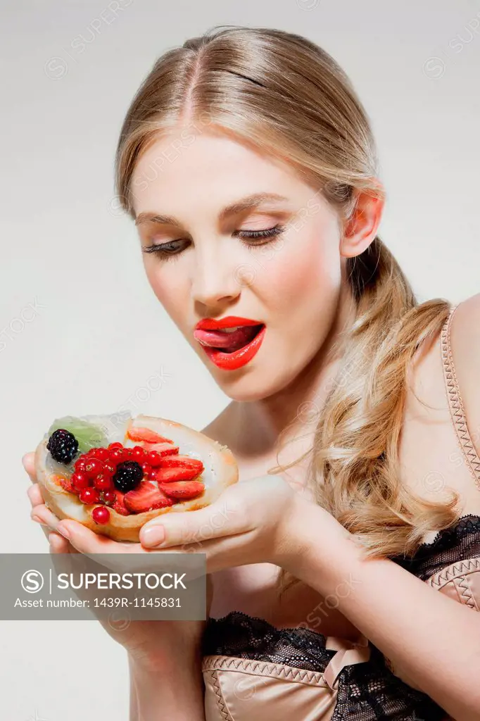 Young woman eating fresh fruit tart